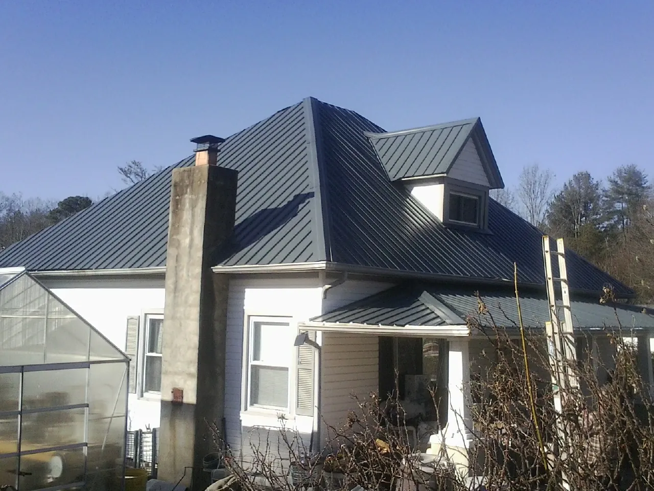 Dark blue standing seam metal roof on a white farmhouse with dormer — Slate & Tile Roof Repair by Roofing Brothers in Tamiment