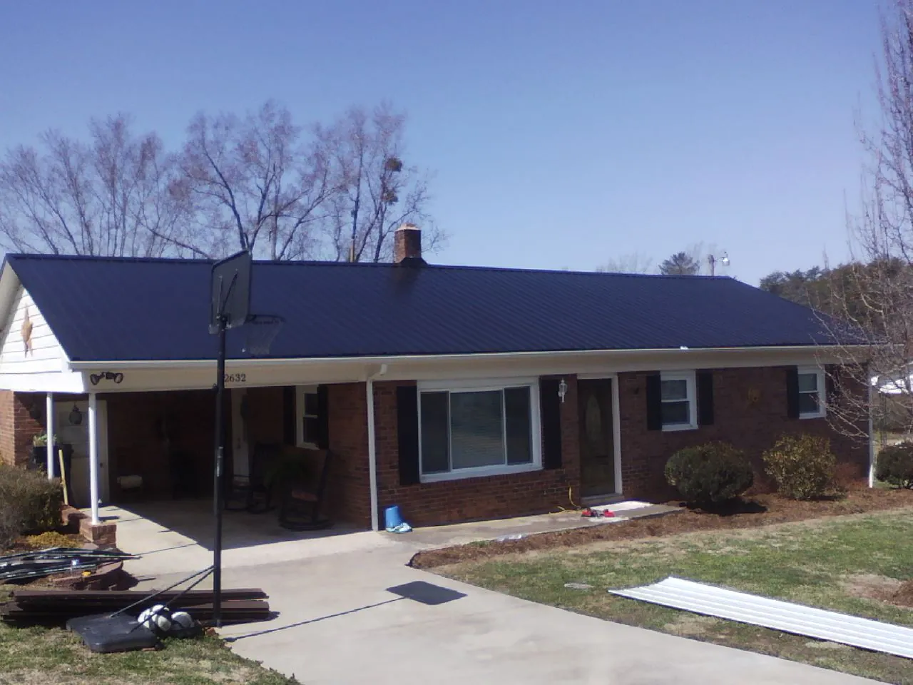 Finished dark blue metal roof on a brick ranch with a carport in Tamiment