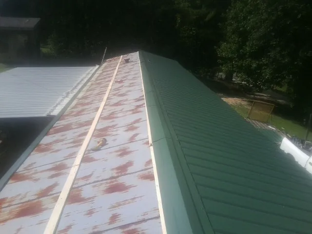 Old rusted panels beside newly installed green metal roofing — Wind Damage Roof Repair by Roofing Brothers in Tamiment