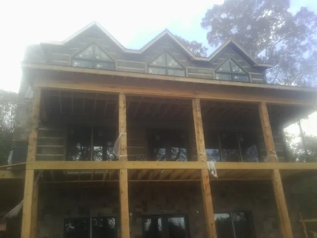 Dormers and porch framing on a large log home under construction — Roof Coating work by our crew in Tamiment