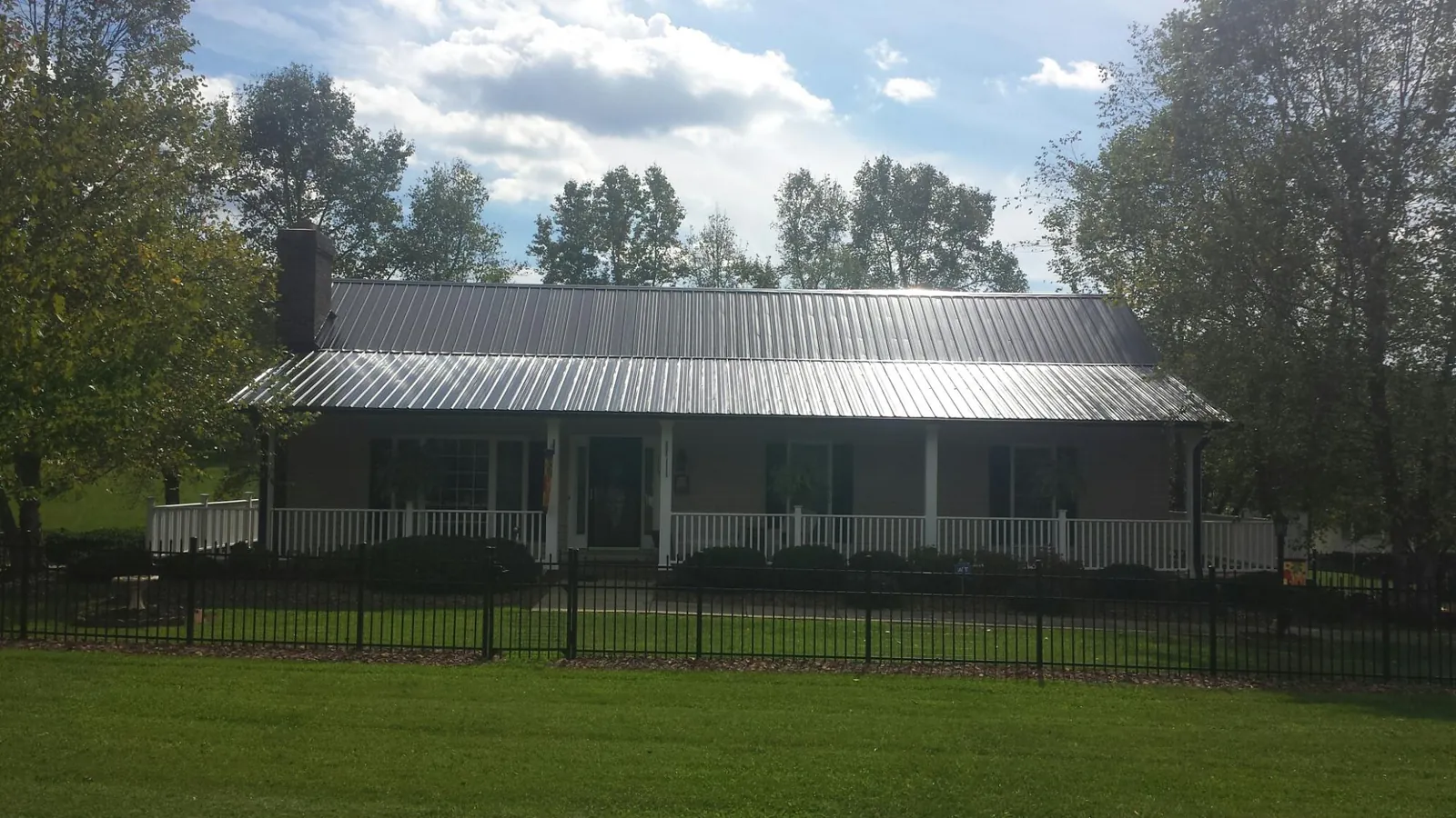 Gray metal roof on a brick ranch with a full width front porch — Gutter Guard Installation work by our crew in Tamiment