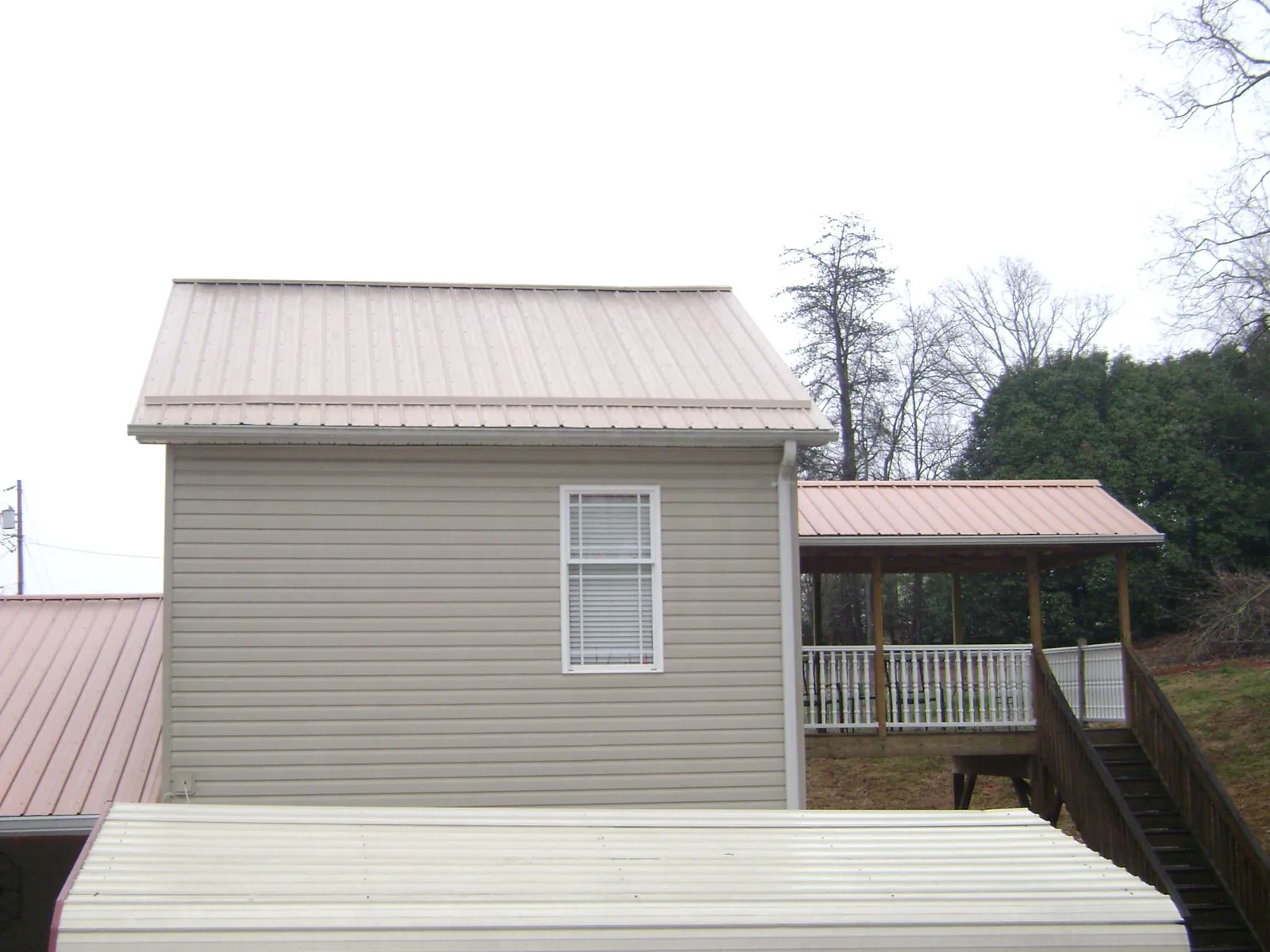 Tan metal roofs on a two story addition and attached porch, from a Roof Replacement job in Tamiment