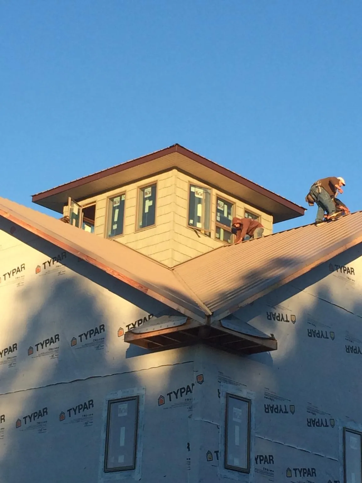 Roofers working around a rooftop cupola on a new metal roof at sunset — Roof Waterproofing in Tamiment by Roofing Brothers